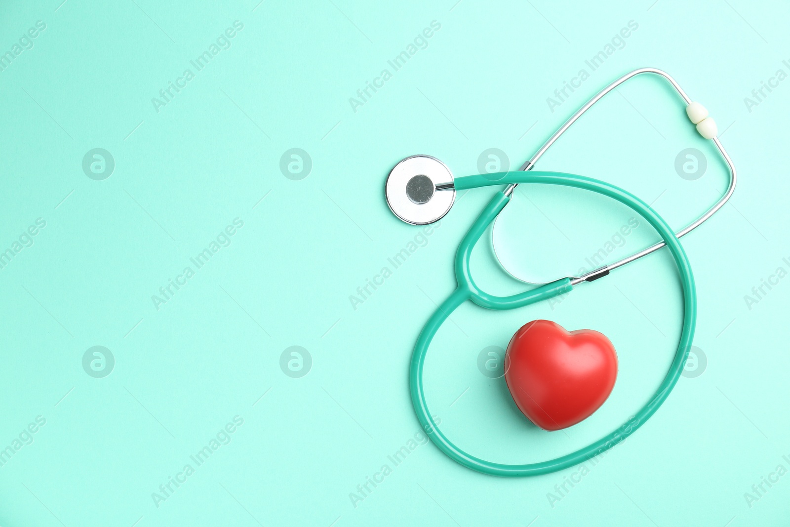 Photo of Cardiology. Stethoscope and red decorative heart on turquoise background, flat lay. Space for text