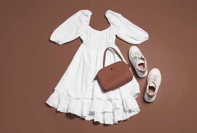 Image of Stylish outfit with bag in mocha mousse shade on brown background, flat lay. Trendy color of 2025 year