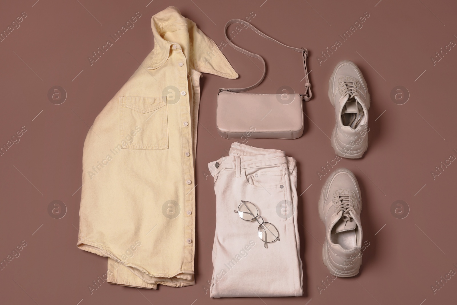 Image of Stylish outfit with bag on mocha mousse shade background, flat lay. Trendy color of 2025 year