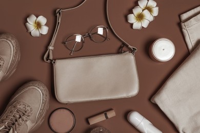 Image of Stylish accessories and makeup products on mocha mousse shade background, flat lay. Trendy color of 2025 year