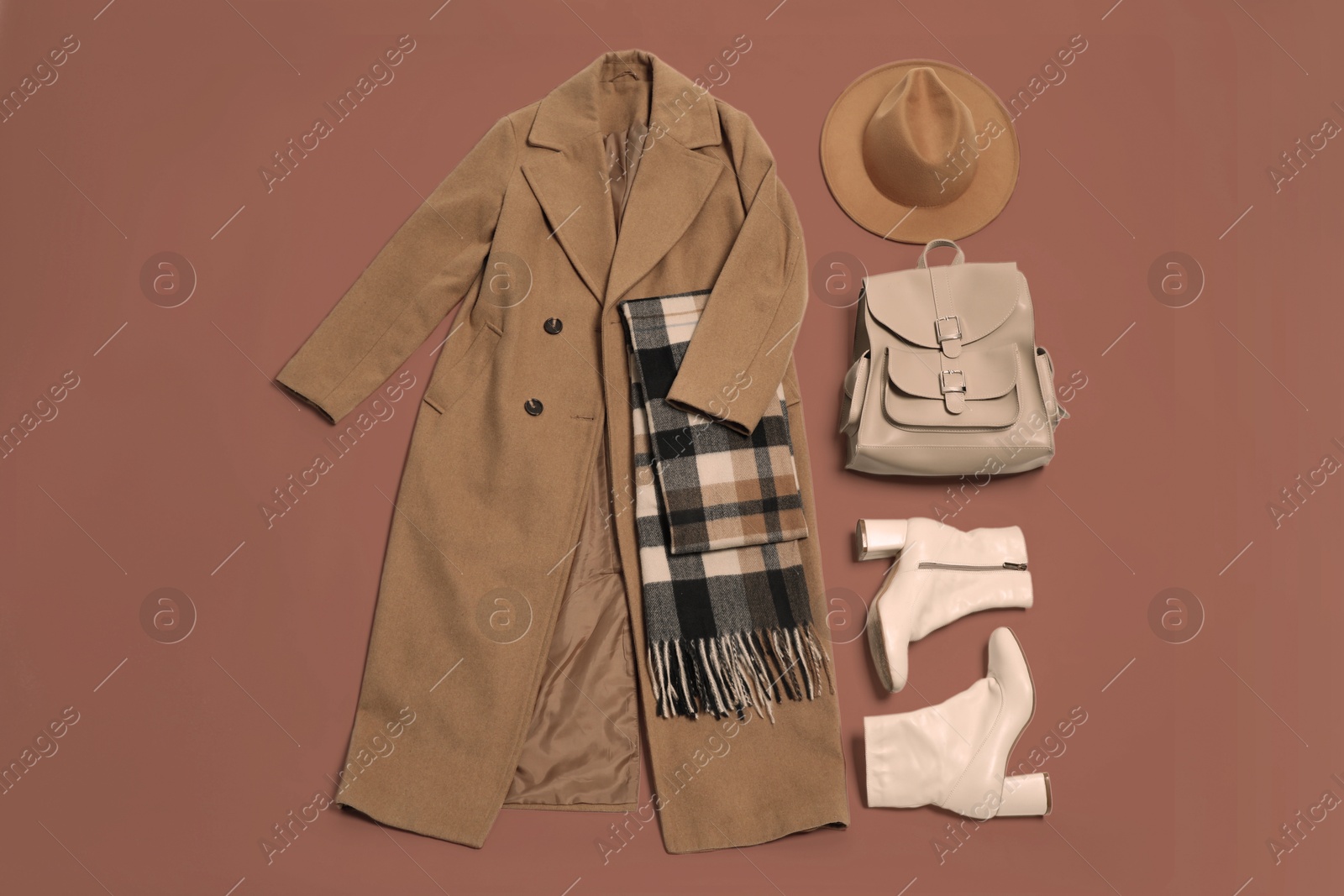 Image of Stylish outfit with backpack in mocha mousse shade on brown background, flat lay. Trendy color of 2025 year