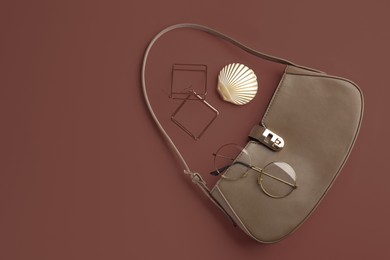 Image of Stylish bag and stylish accessories on mocha mousse shade background, flat lay. Trendy color of 2025 year