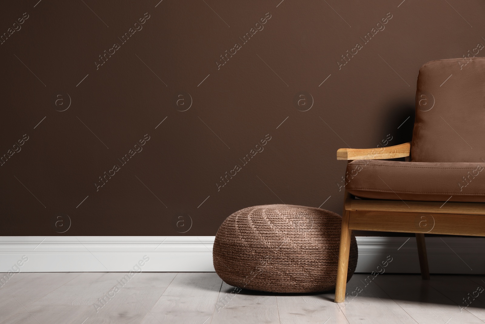 Image of Stylish interior in mocha mousse shade. Armchair, pouf and wall in trendy color of 2025 year