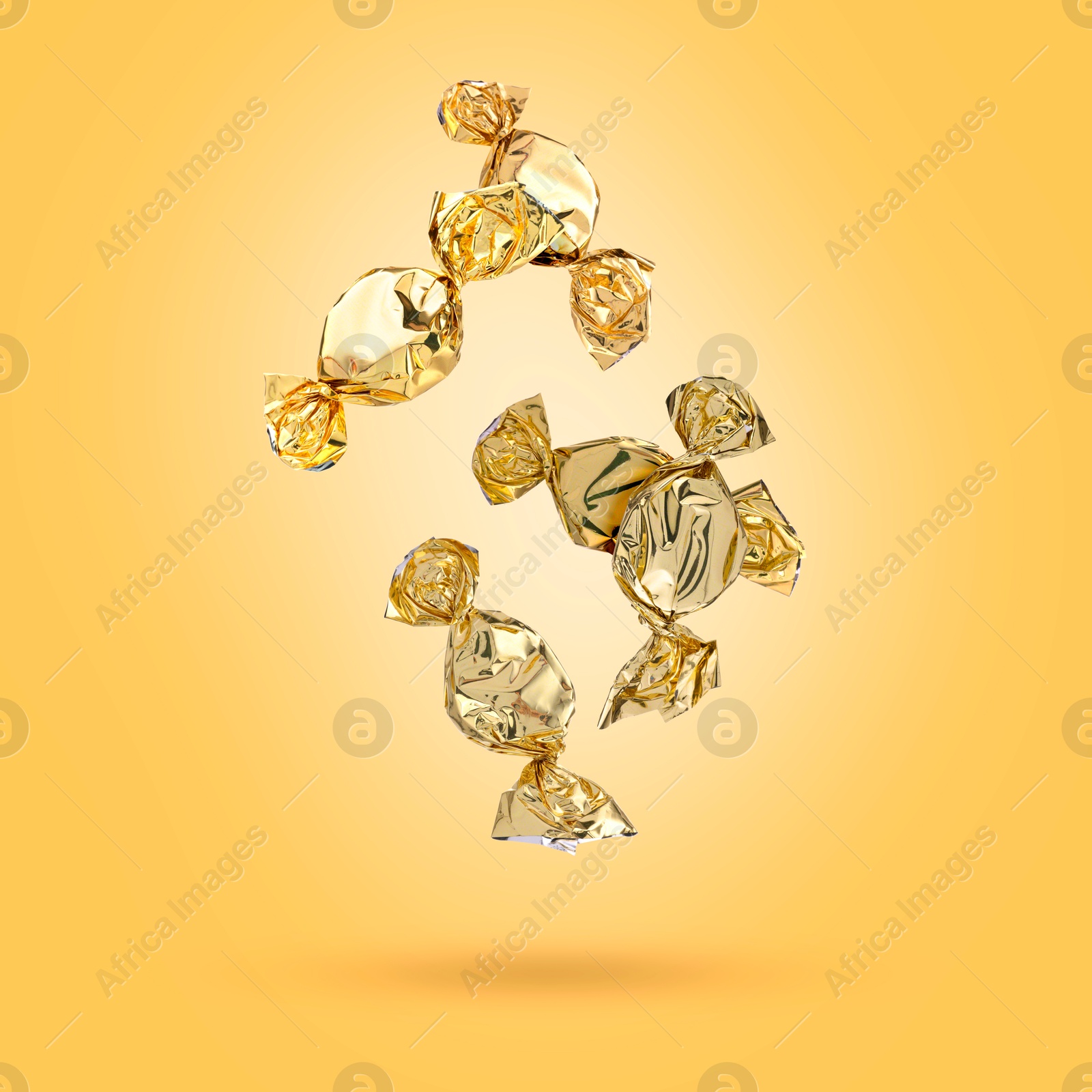 Image of Candies in bright wrappers falling on orange background