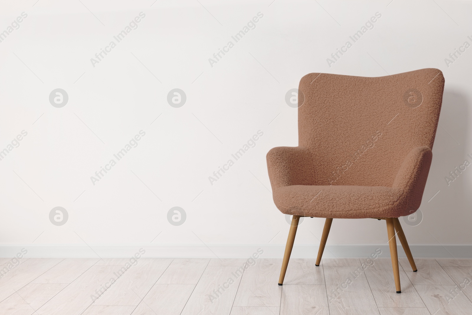 Image of Armchair in mocha mousse shade near white wall indoors. Interior with trendy color of 2025 year