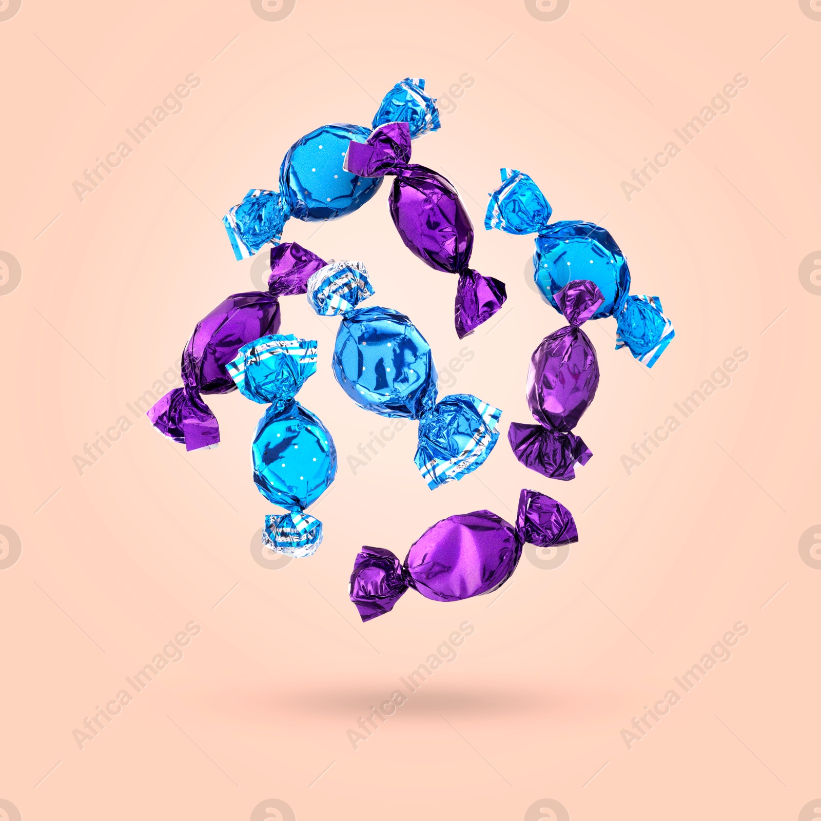 Image of Candies in bright wrappers falling on pink background