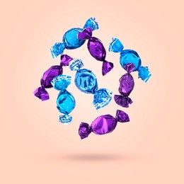 Image of Candies in bright wrappers falling on pink background