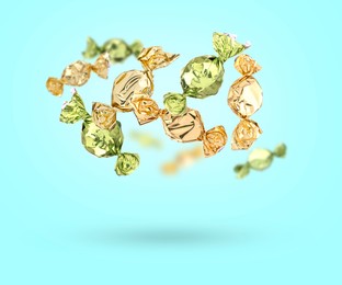 Image of Candies in bright wrappers falling on light blue background