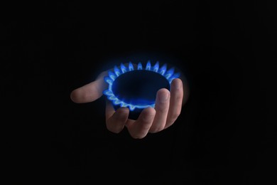 Image of Woman holding gas burner with blue flame on black background, closeup