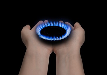 Image of Woman holding gas burner with blue flame on black background, closeup