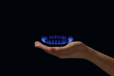 Image of Woman holding gas burner with blue flame on black background, closeup