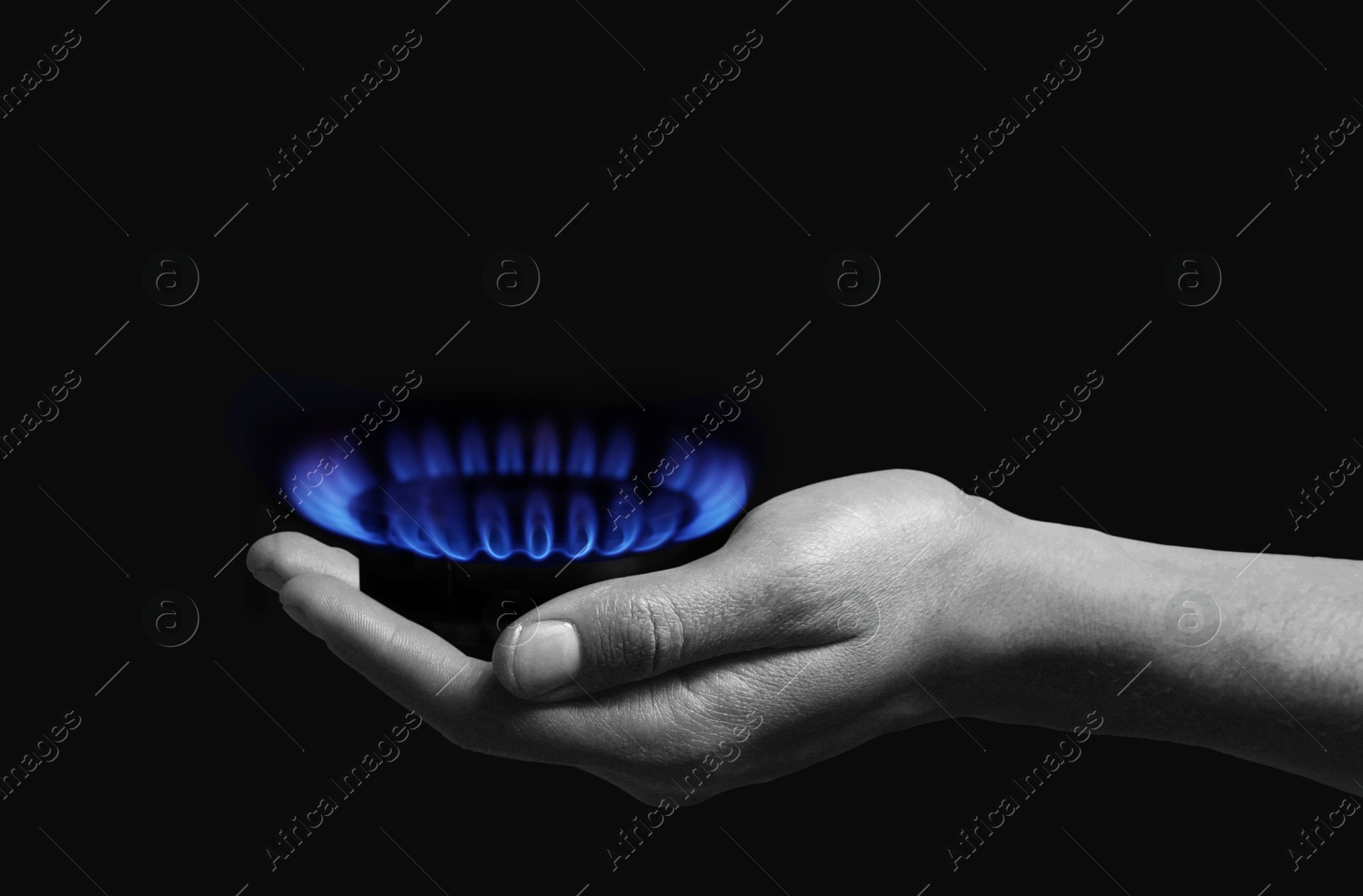 Image of Woman holding gas burner with blue flame on black background, closeup. Black and white effect with color accent