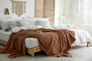 Image of Large bed with blanket in mocha mousse shade indoors. Stylish bedroom interior with trendy color of 2025 year