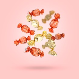 Image of Candies in bright wrappers falling on pink background