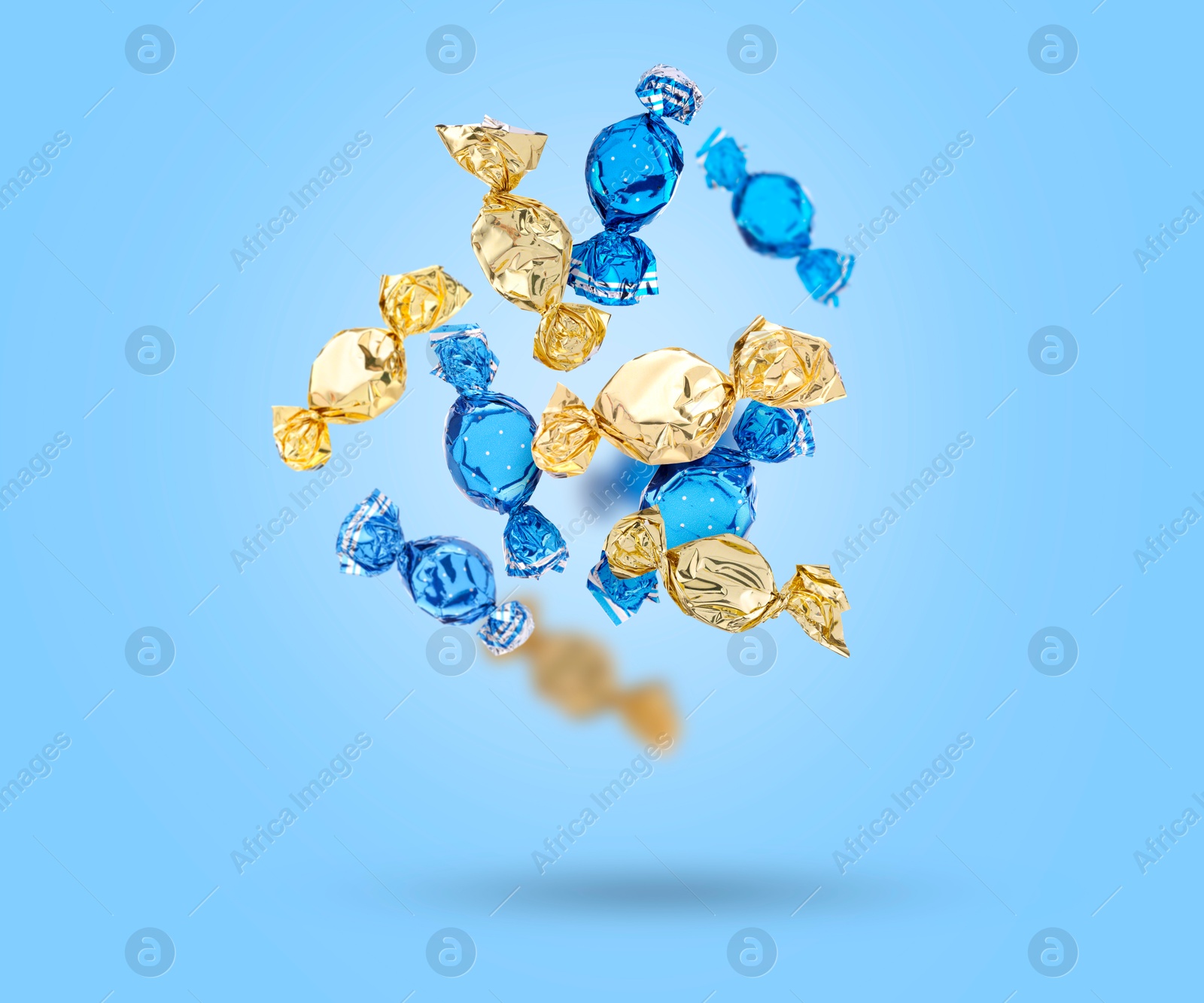 Image of Candies in bright wrappers falling on light blue background