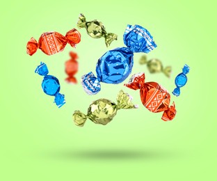 Image of Candies in bright wrappers falling on light green background