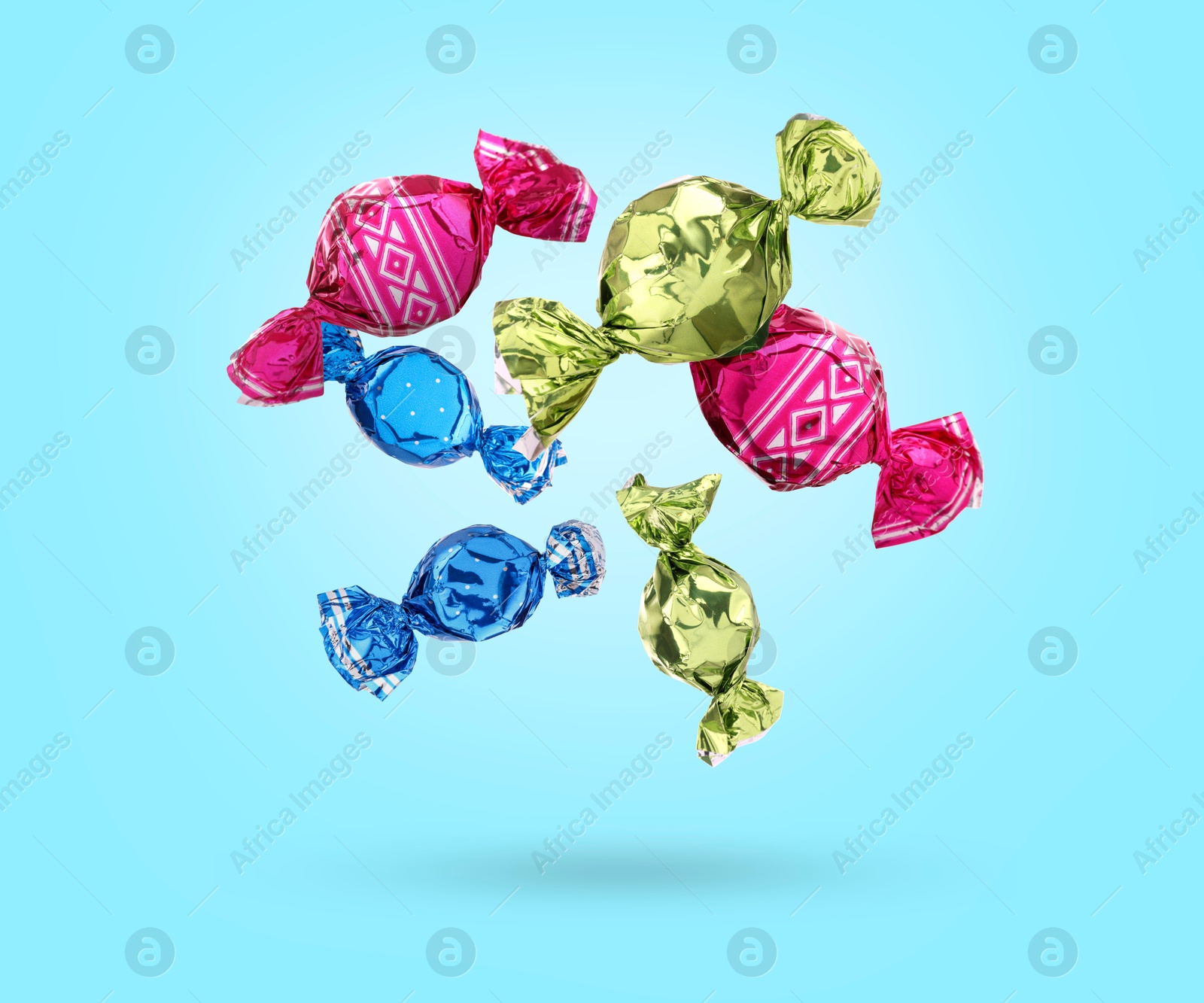 Image of Candies in bright wrappers falling on light blue background