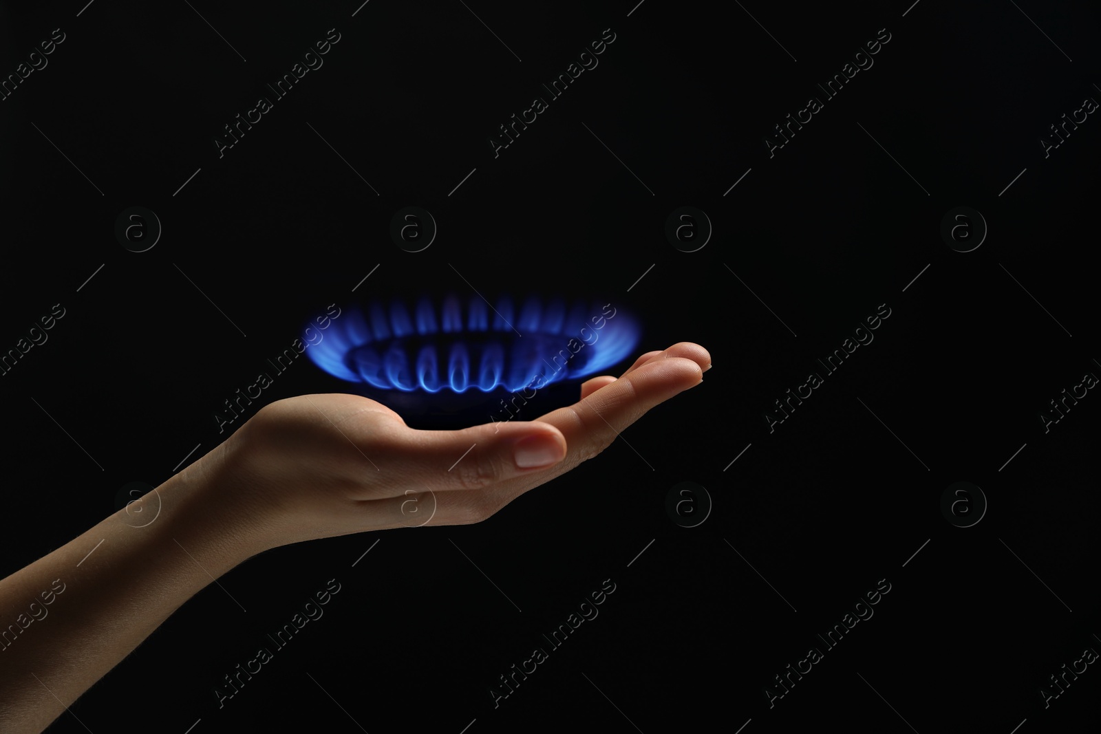 Image of Woman holding gas burner with blue flame on black background, closeup