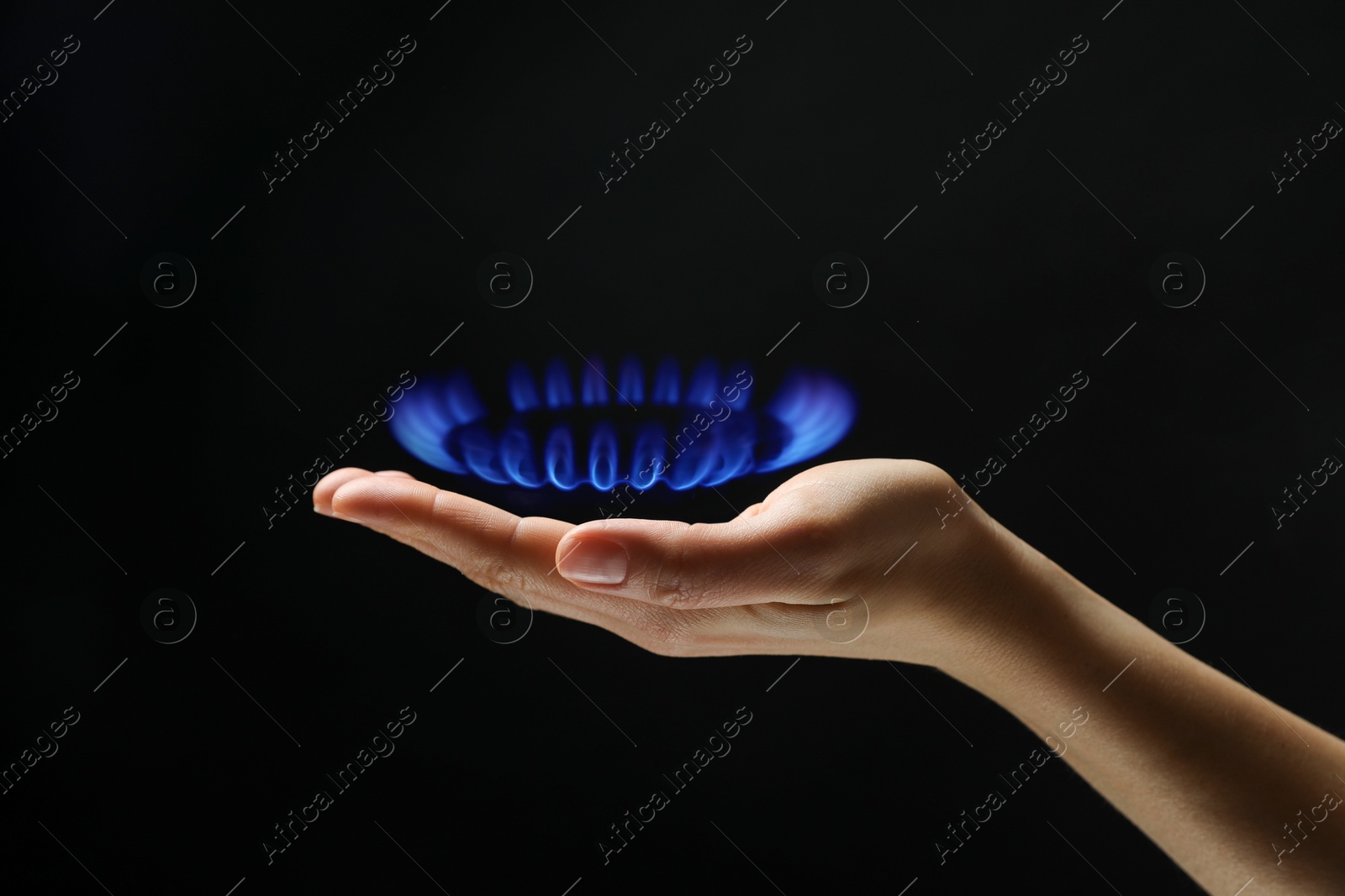 Image of Woman holding gas burner with blue flame on black background, closeup