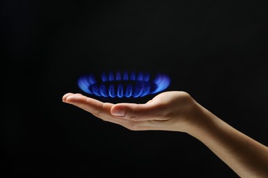 Image of Woman holding gas burner with blue flame on black background, closeup