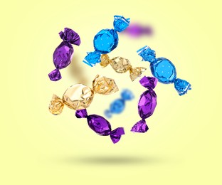 Image of Candies in bright wrappers falling on color background