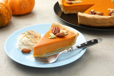 Photo of Piece of tasty homemade pumpkin pie with whipped cream, seeds and nuts on grey table, closeup