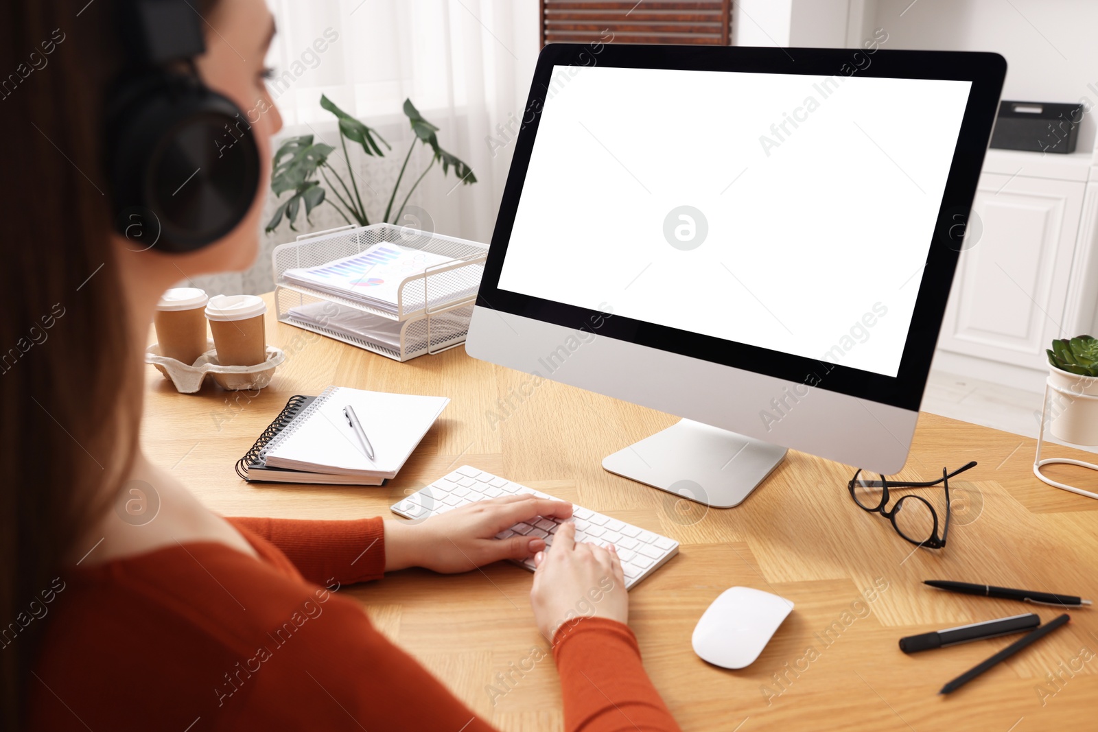 Photo of Woman working on computer at wooden table in office, closeup