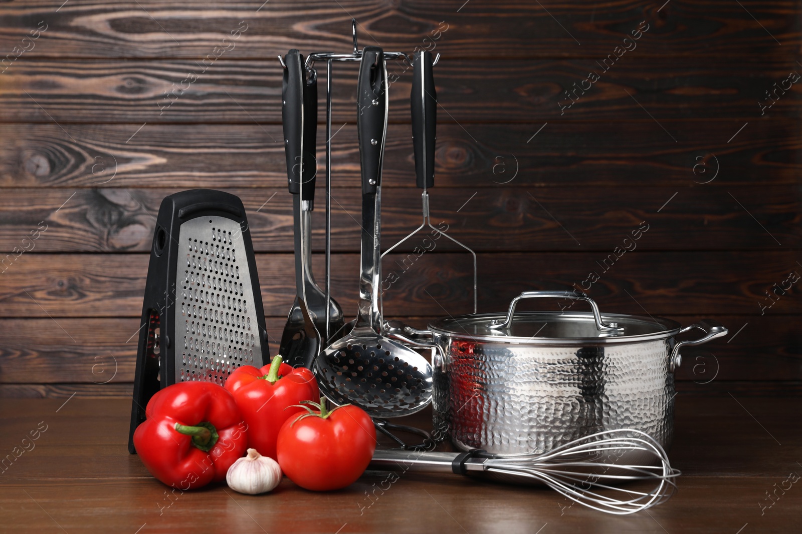 Photo of Dishware and cooking utensils with vegetables on wooden table