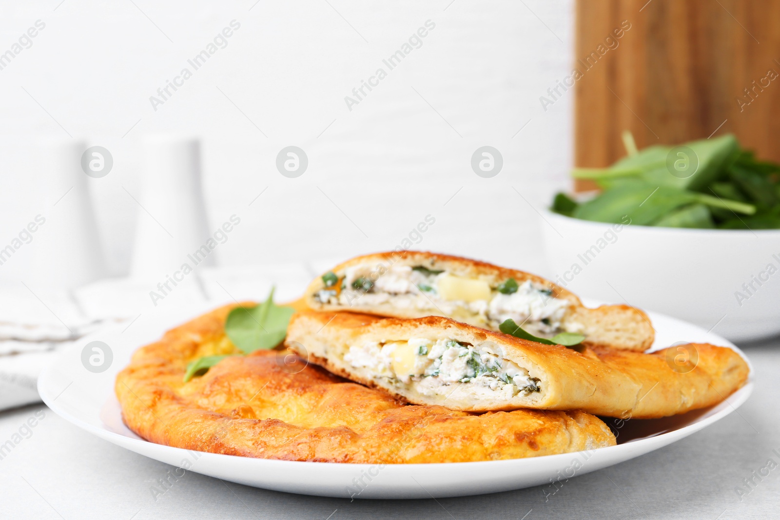 Photo of Tasty calzones with cheese and basil on light grey table, closeup