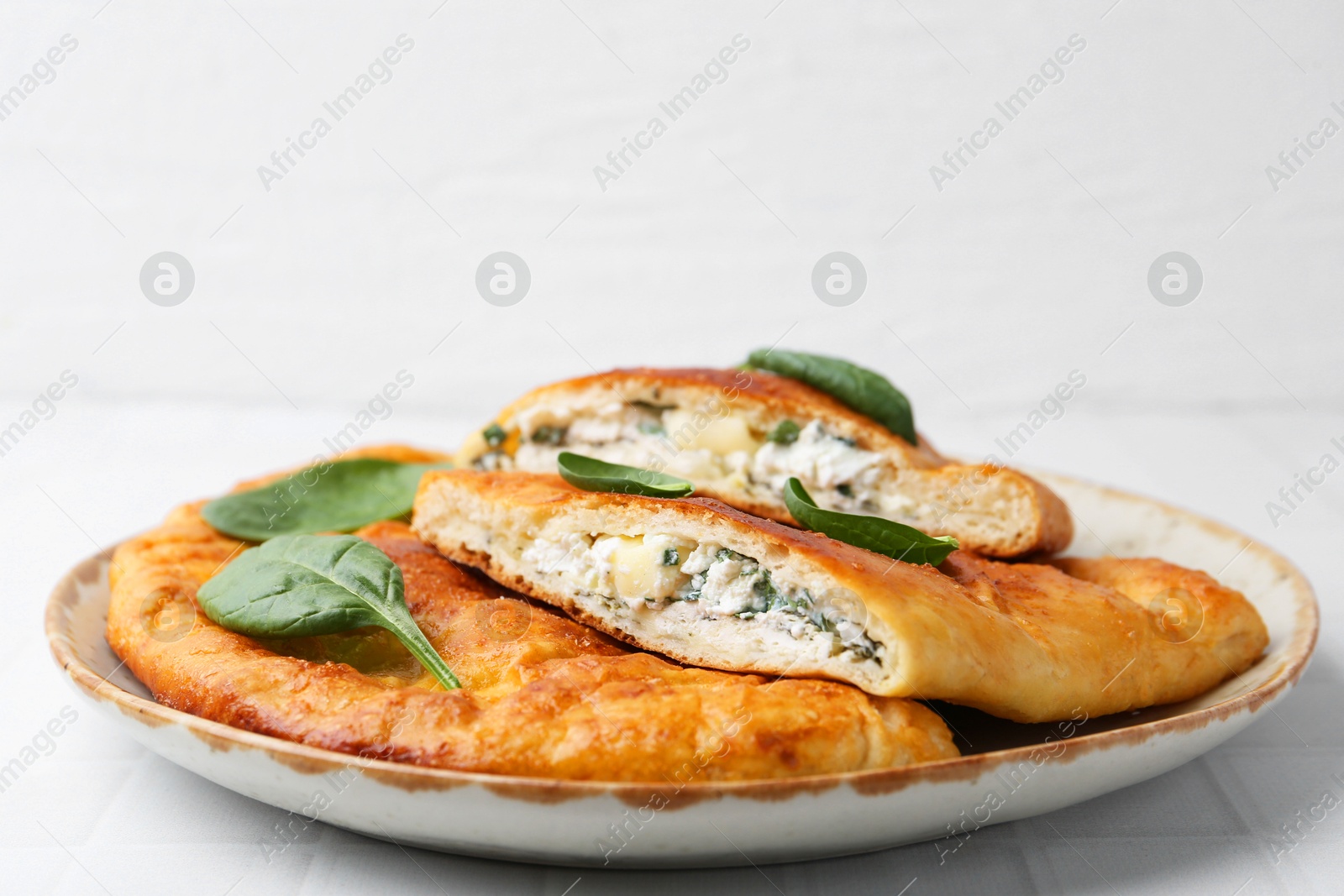 Photo of Tasty calzones with basil and cheese on white table, closeup