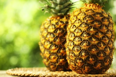 Photo of Fresh ripe pineapples on table against blurred background, closeup. Space for text