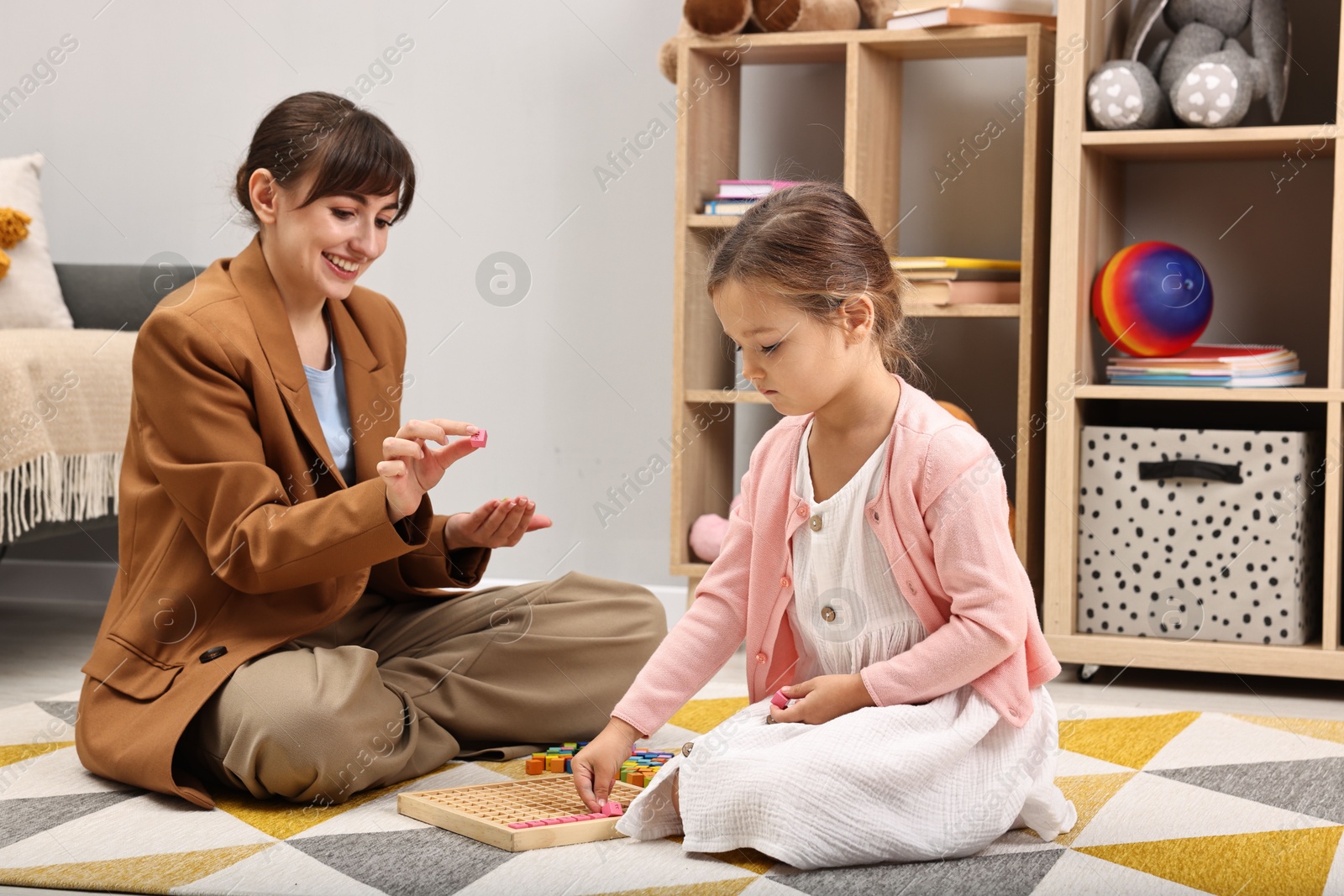 Photo of Autism therapy. Smiling psychologist and little girl playing with educational toy in mental health center