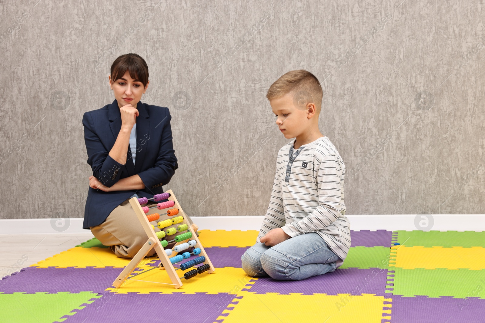 Photo of Psychologist observing little boy playing in autism treatment center