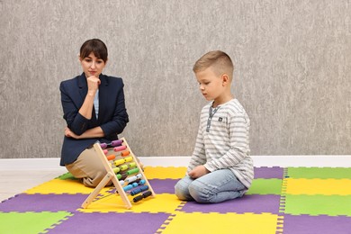 Photo of Psychologist observing little boy playing in autism treatment center