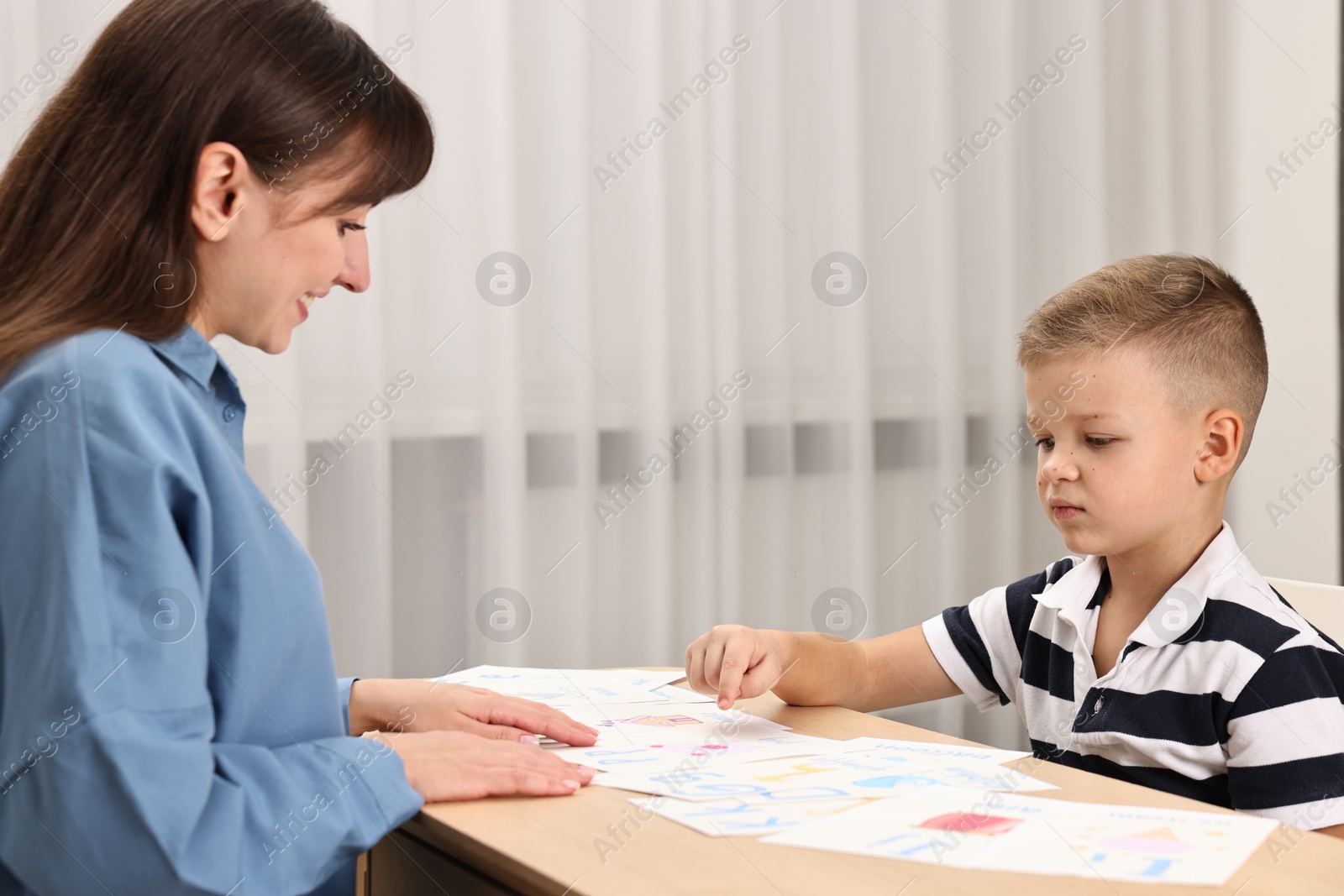 Photo of Speech therapist working with little boy at table in autism treatment center