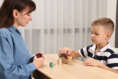 Photo of Autism therapy. Psychologist and little boy playing with educational toy at table in mental health center