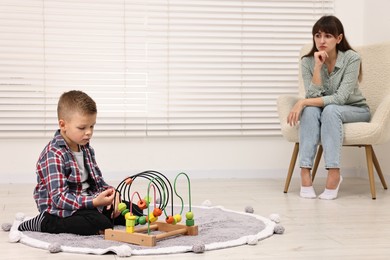 Photo of Psychologist observing little boy playing in autism treatment center