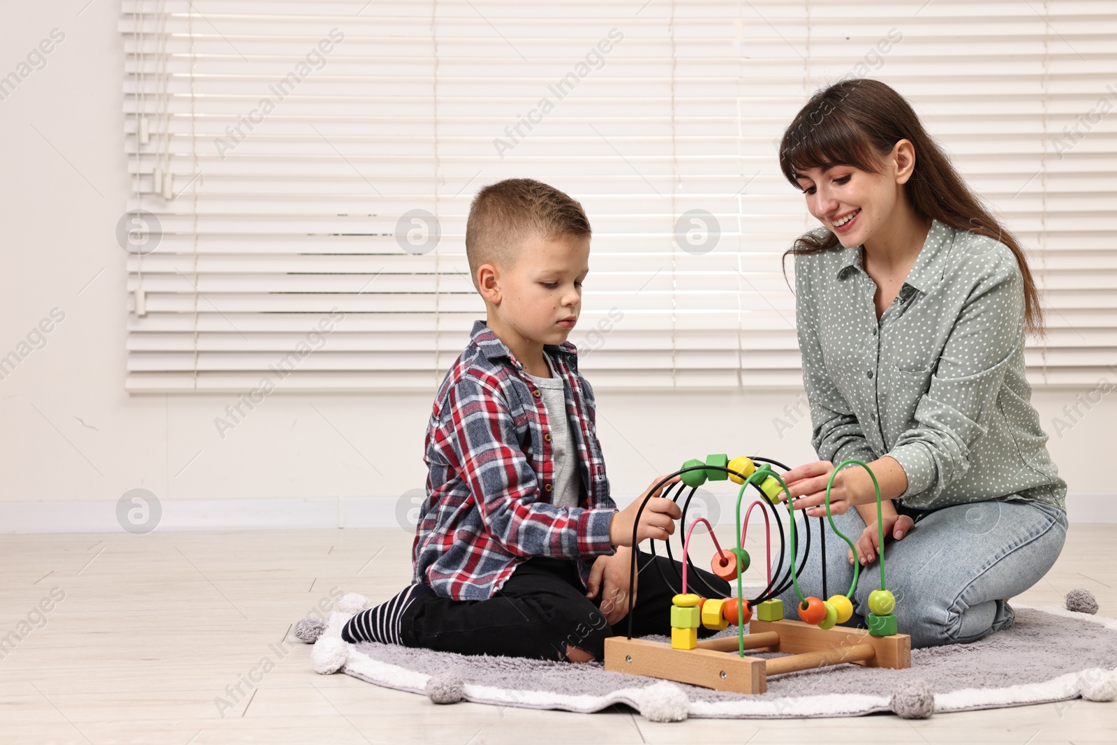 Photo of Autism therapy. Smiling psychologist and little boy playing with educational toy in mental health center, space for text