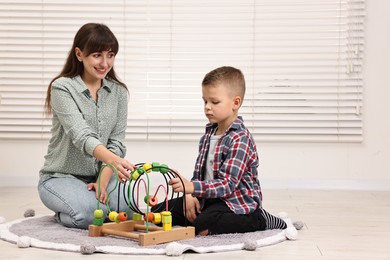 Photo of Autism therapy. Smiling psychologist and little boy playing with educational toy in mental health center, space for text