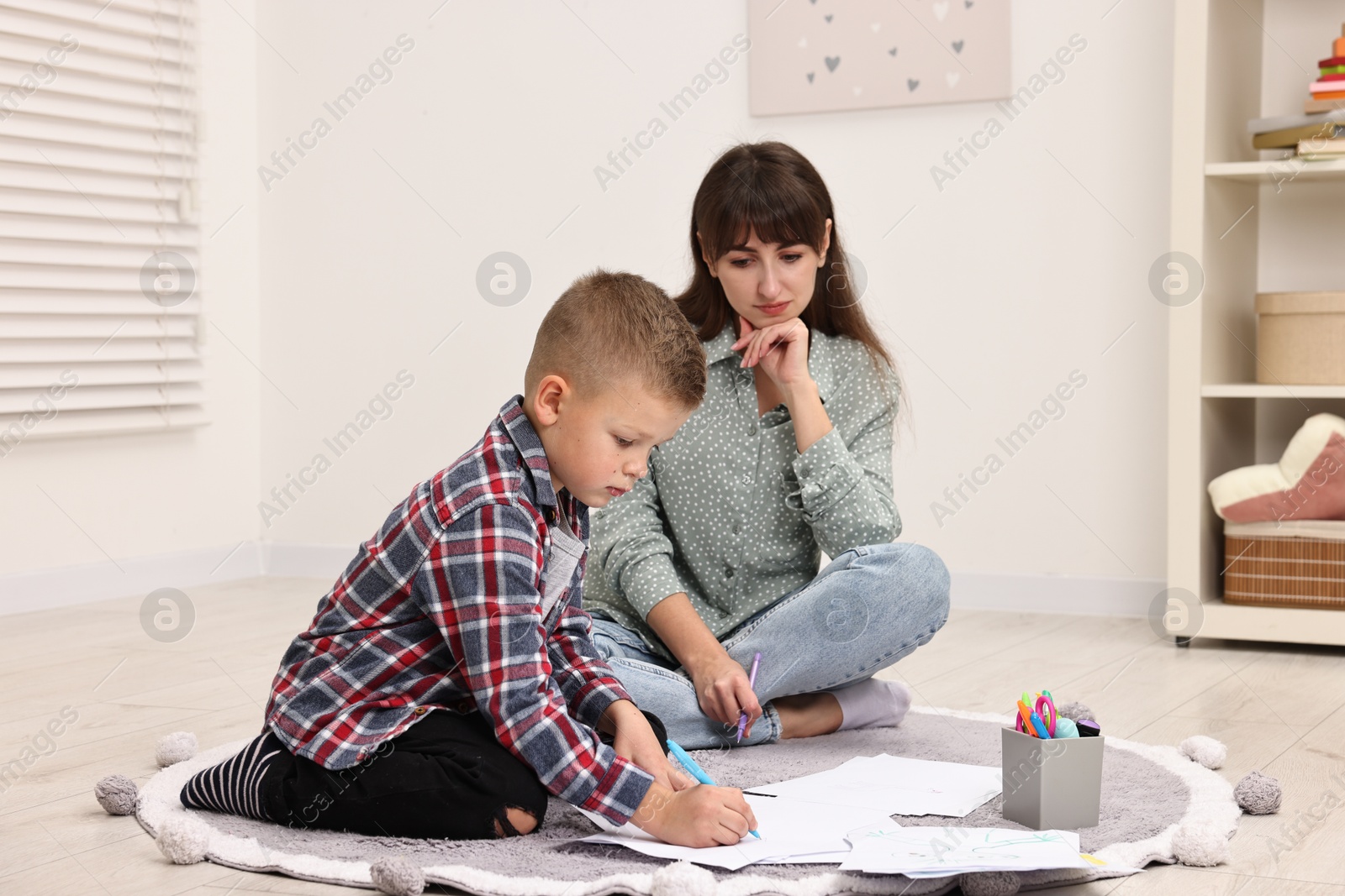 Photo of Therapist observing little boy drawing in autism treatment center