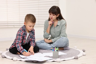 Photo of Therapist observing little boy drawing in autism treatment center