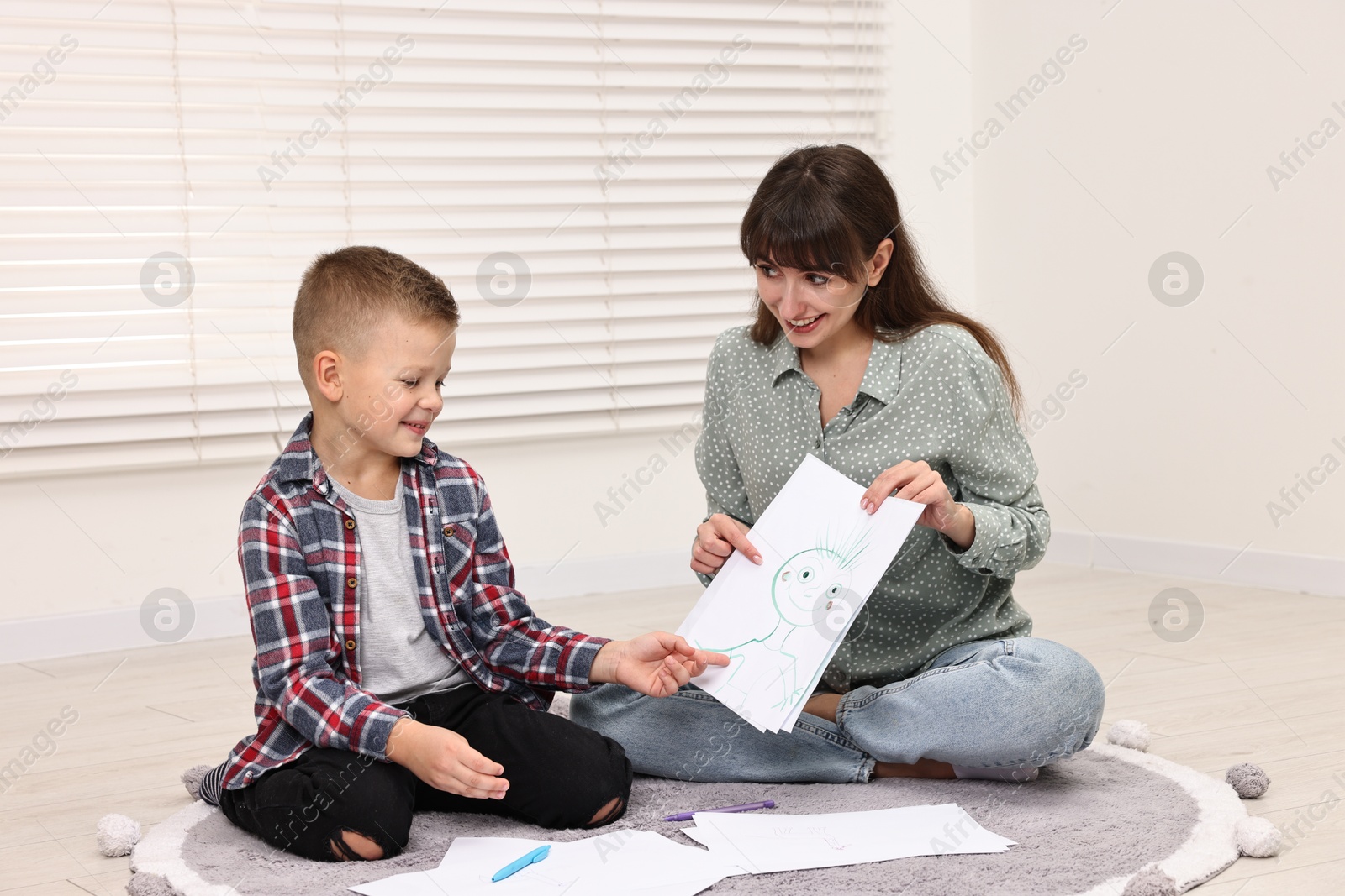 Photo of Smiling psychologist working with little boy in autism treatment center