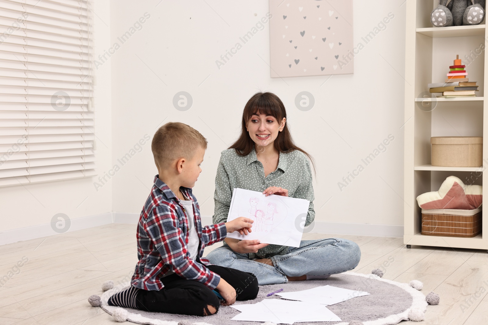 Photo of Smiling psychologist working with little boy in autism treatment center