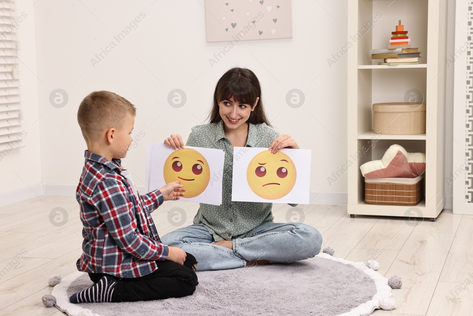 Photo of Autism therapy. Little boy choosing emoticon with smiling psychologist in mental health center