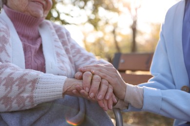 Photo of Caregiver with elderly woman in park, closeup