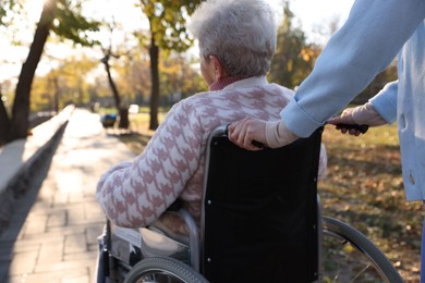 Photo of Caregiver with elderly woman in wheelchair at park, closeup