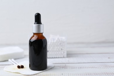 Photo of Bottle of iodine with dropper, cotton pads and swabs on white wooden table, closeup. Space for text