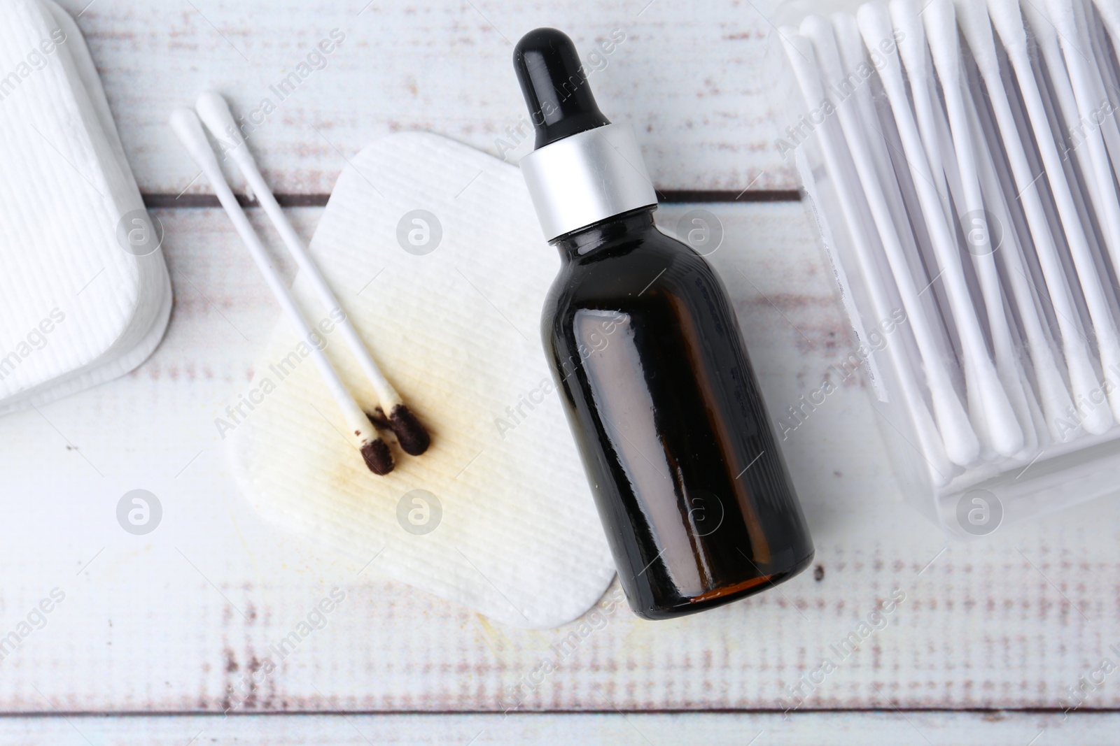 Photo of Bottle of iodine with dropper, cotton pads and swabs on white wooden table, flat lay