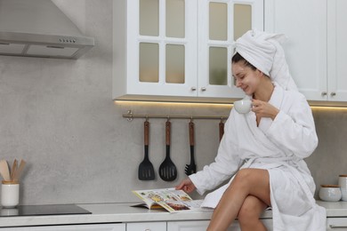 Photo of Spa day. Beautiful woman with face mask and cup of drink reading magazine in kitchen