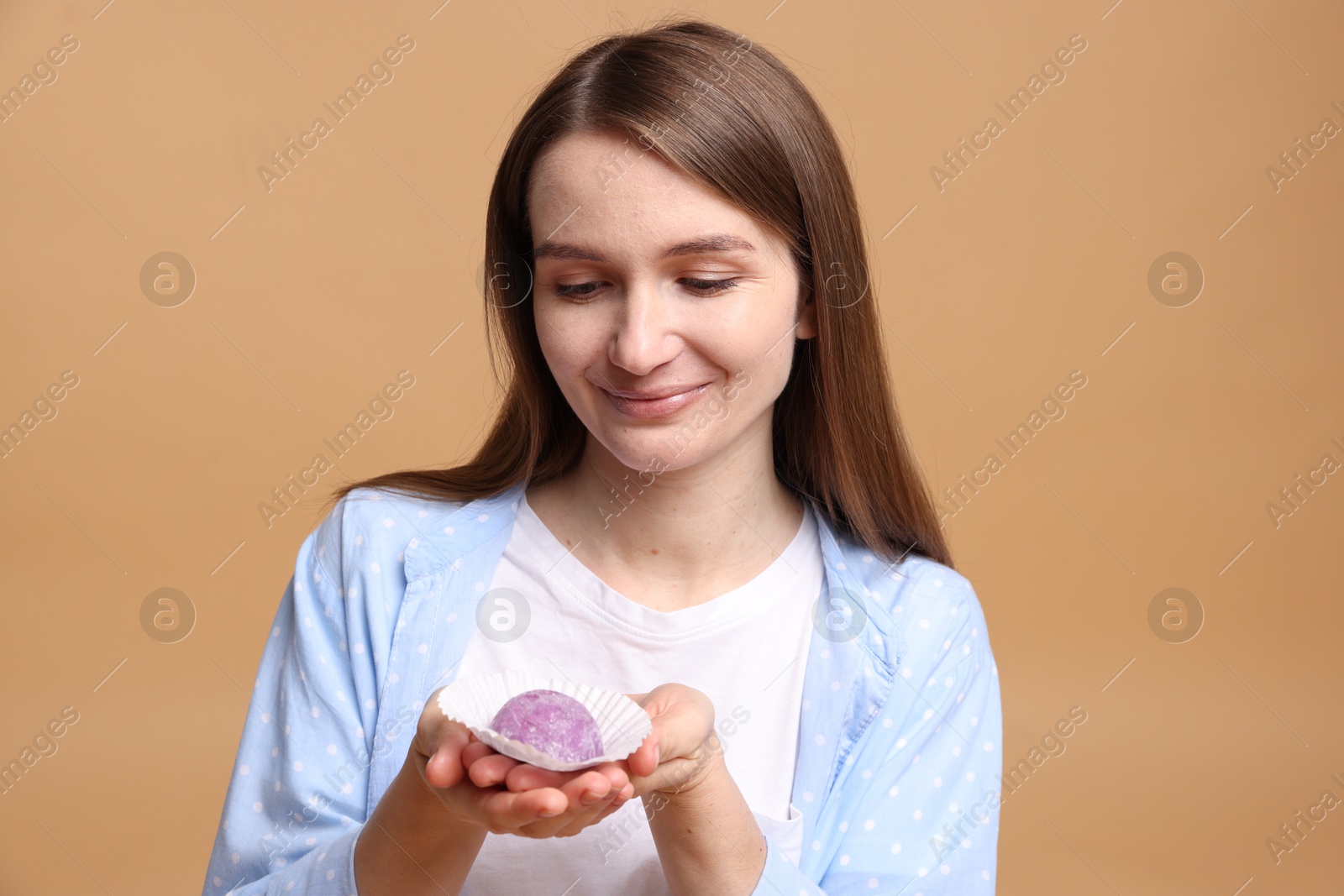 Photo of Woman with tasty mochi on light brown background